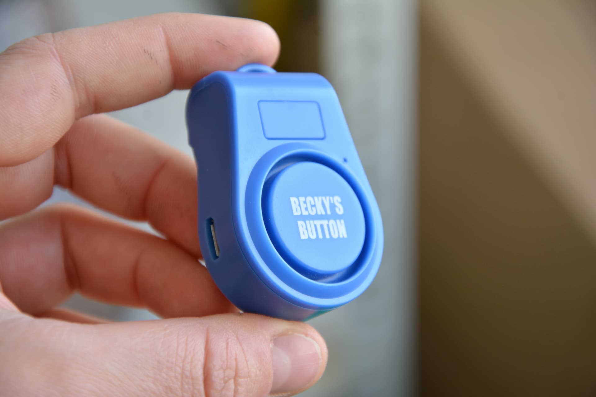 A blue personal safety alarm held in a hand